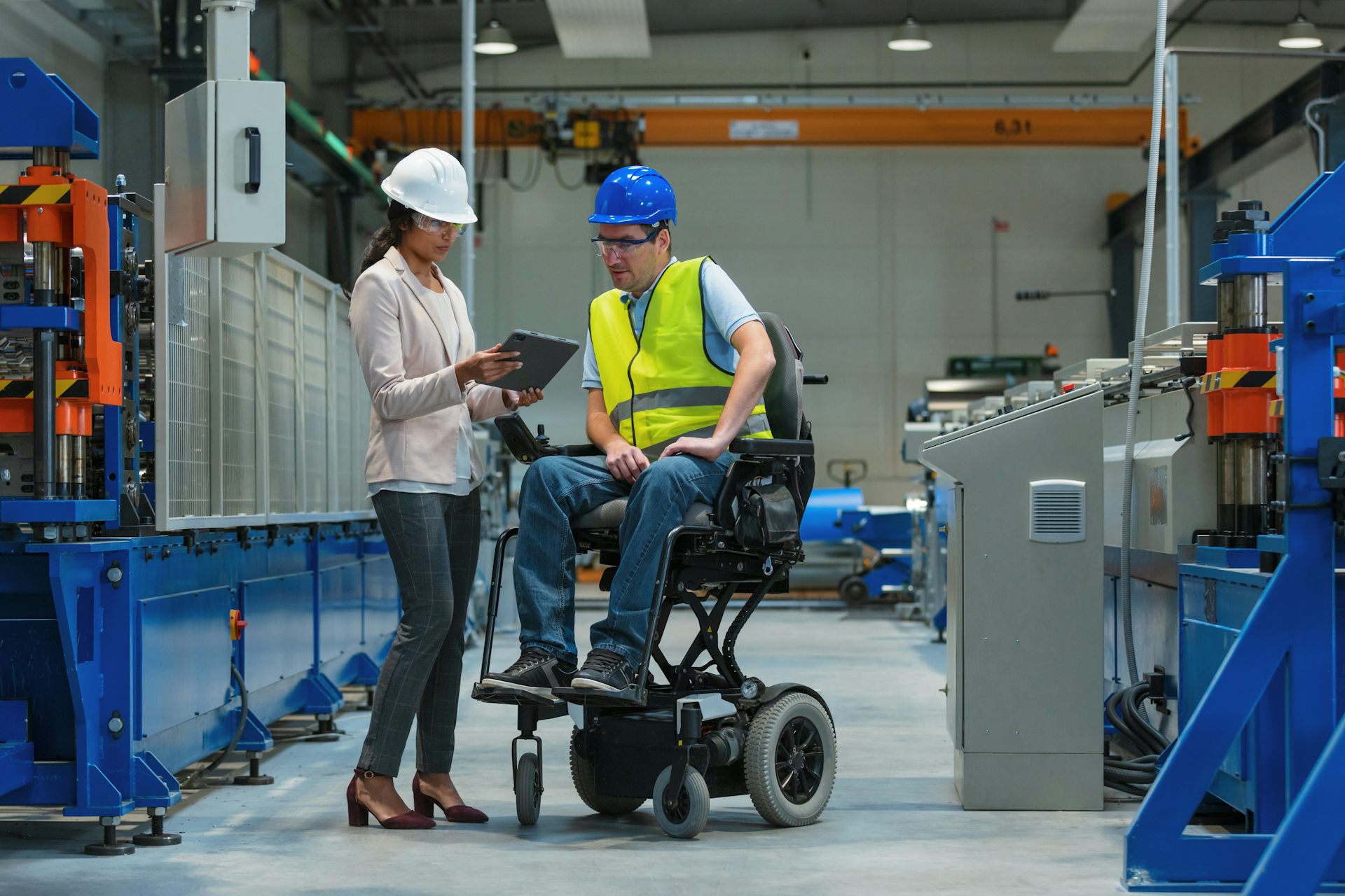 Un homme en fauteuil roulant discute avec une collègue dans une usine