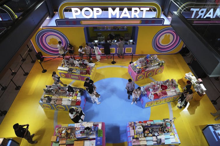 Greathead Vistas de los clientes revisando los estantes de juguetes en un piso amarillo