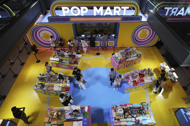 Overhead view of shoppers browsing shelves of toys in a store with a yellow floor