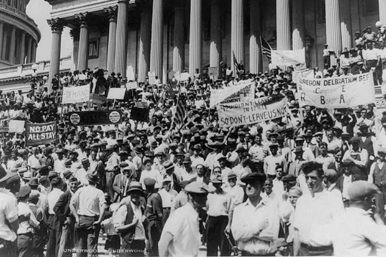 A large group of demonstrators in front of a massive stone building, holding signs.