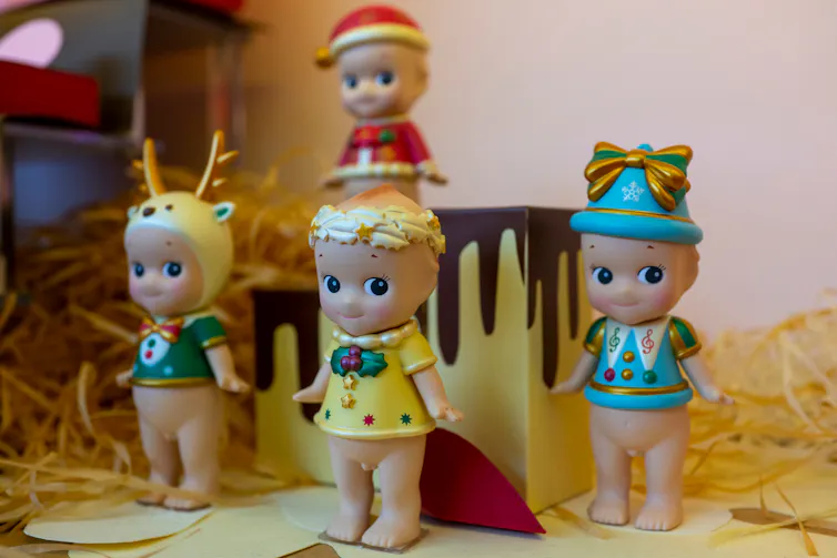 Small collectible dolls that are baby-like in appearance stand on display