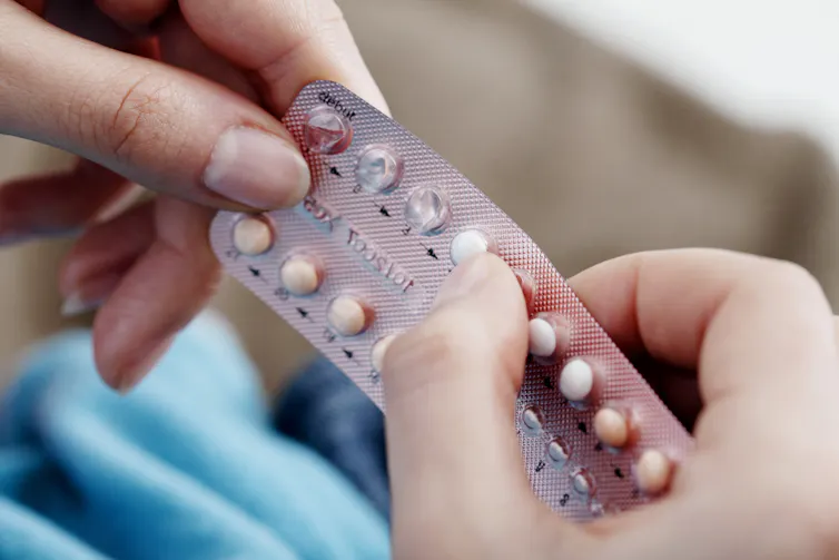 A woman holds a blister pack of birth control pills.