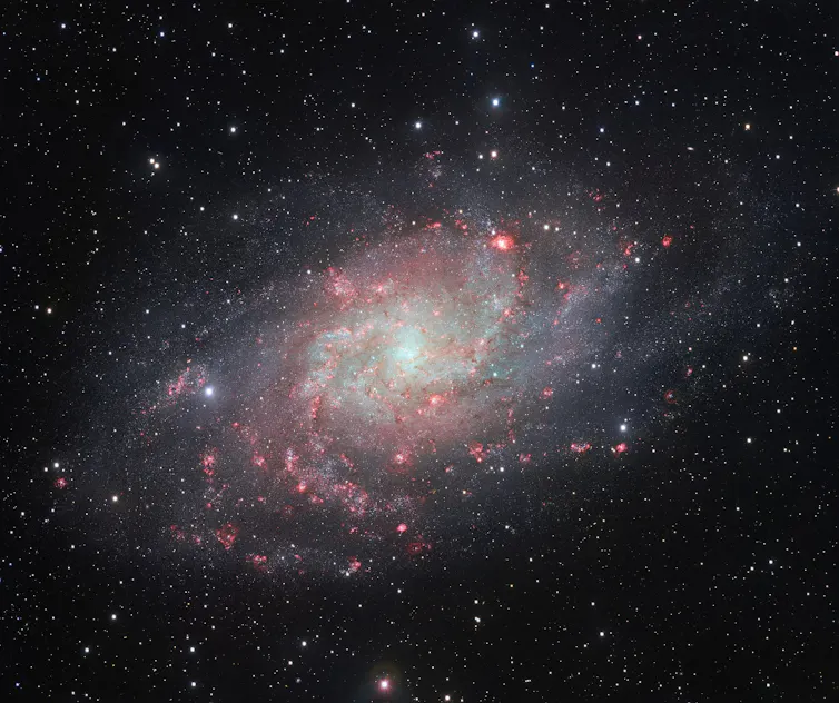 A detailed photo of a white-and-pink pinwheel-shaped galaxy.