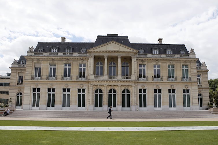 A man walks past the outside of the OECD's headquarters in Paris, France.
