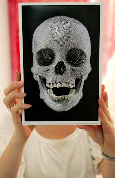 Photo of diamond-encrusted skull held up by unseen person.