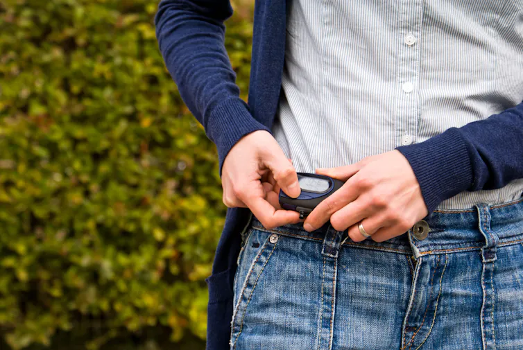 A woman checks a pedometer on her hip.