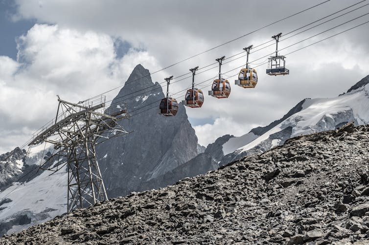 Vue d’un pylone du téléphérique et de plusieurs nacelles, depuis le sol