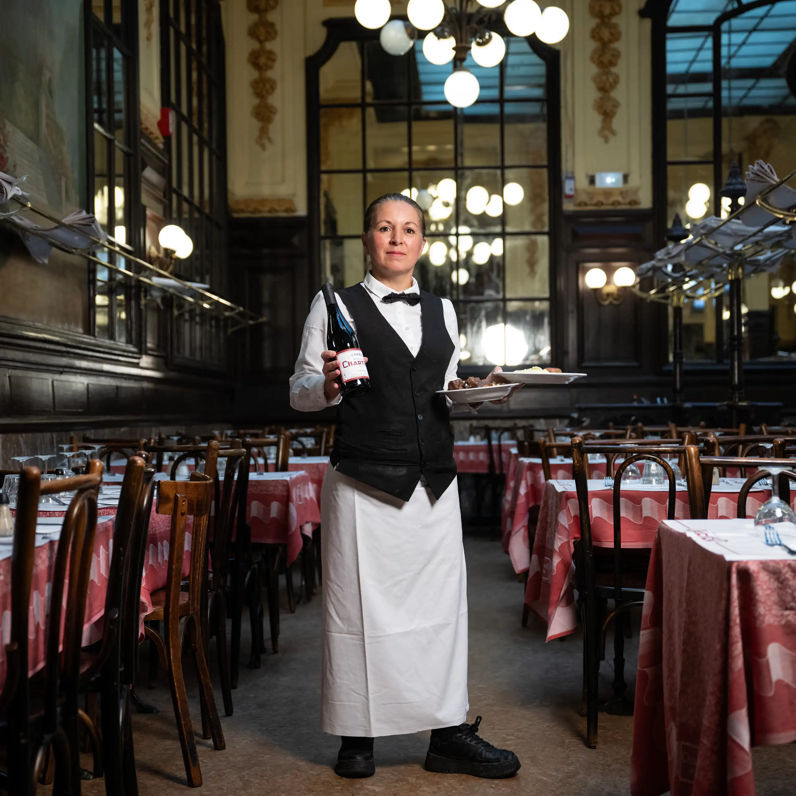 Portrait en pied de Fati, cheffe de rang Bouillon Chartier, posant dans la grande salle de son établissement.