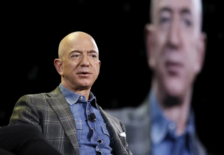 A bald white man in a suit speaks at a convention