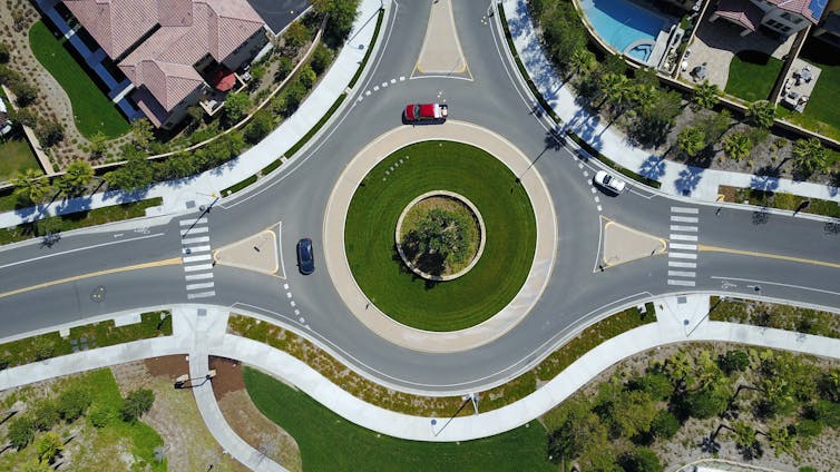 An aerial view of a cars traveling around a roundabout.