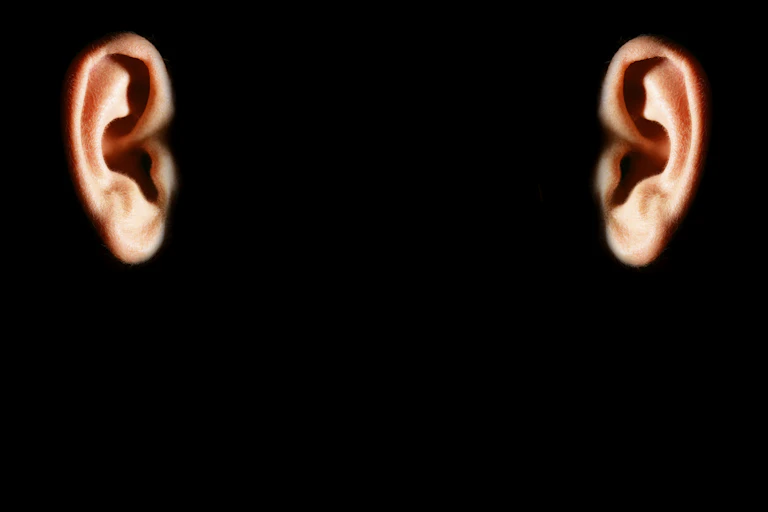 Two disembodied ears against a black background