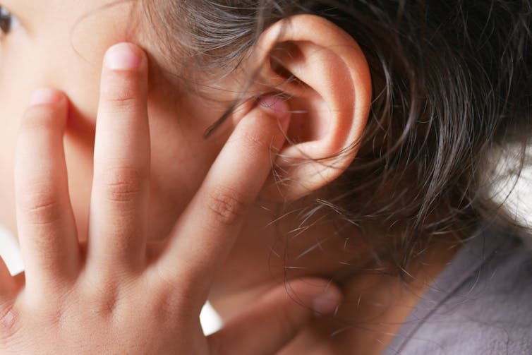 Close-up of child holding finger to ear