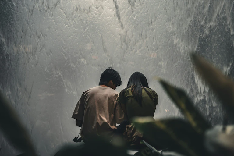 The backs of a male and female couple holding each other and looking down