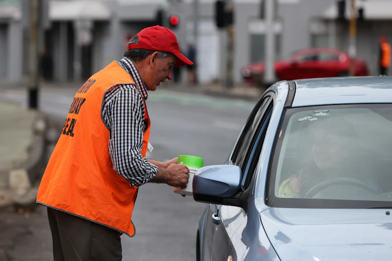 volunteer collecting donations in stopped traffic