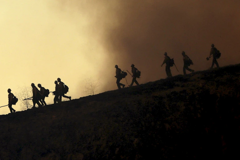 Silhouetted human figures on smoky hillside.