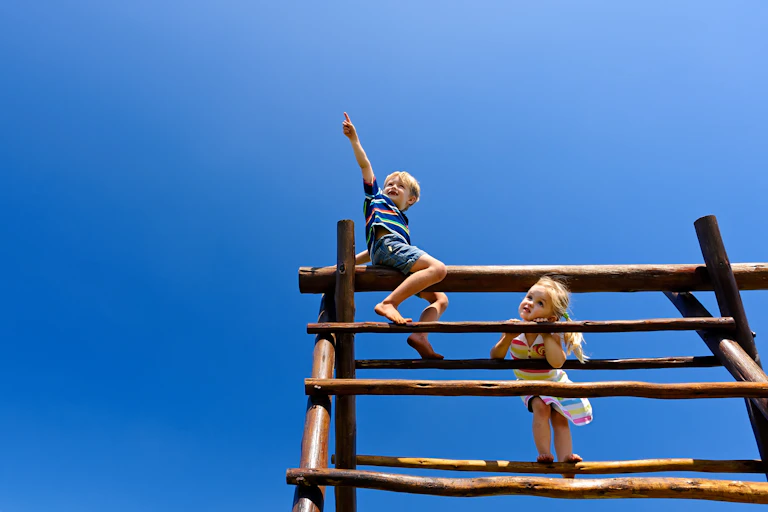 Two children on top of a wooden climbing frame