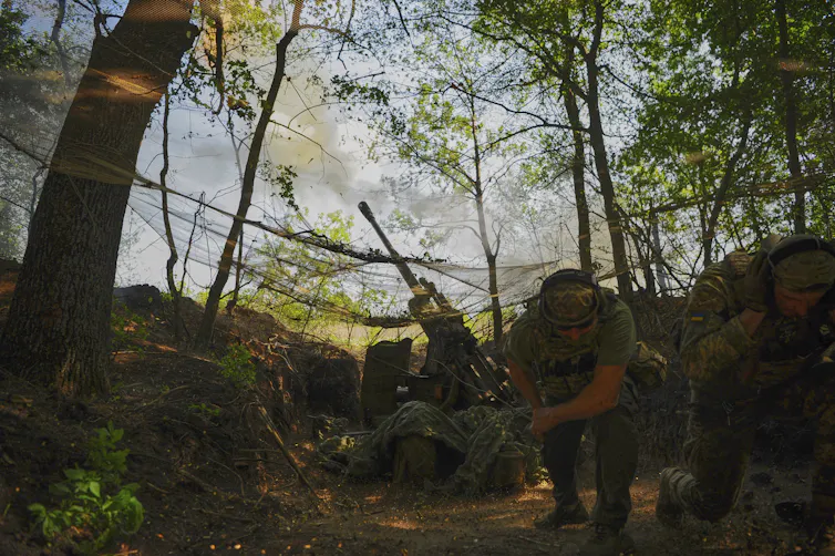 Soldiers in the woods firing a cannon.