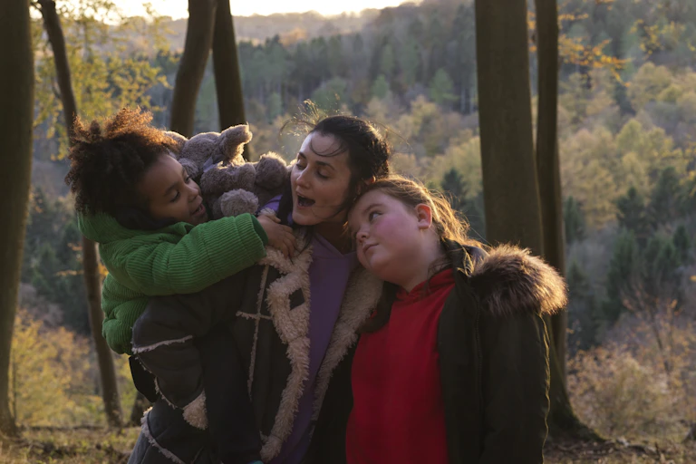 A mother hugging her two daughters.