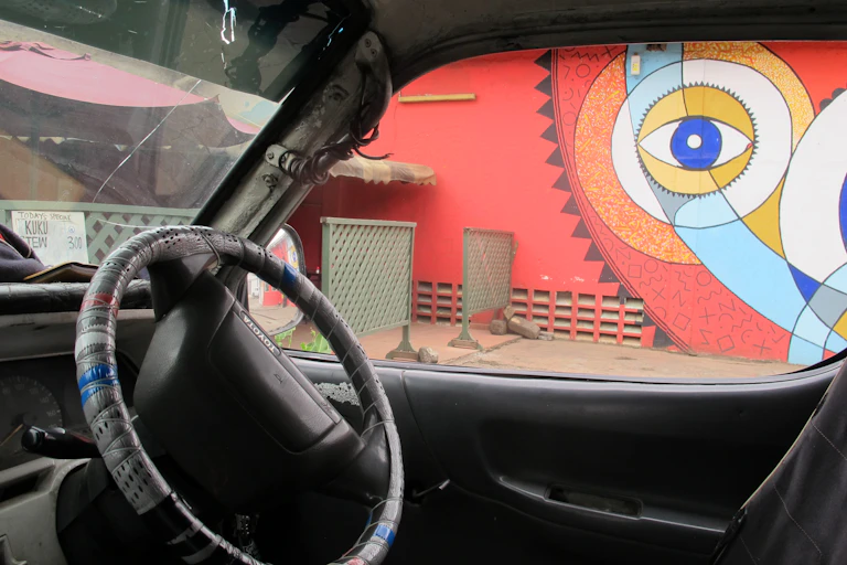 The view from a car of a bright red painting on a wall featuring circles around a stylised human eye.