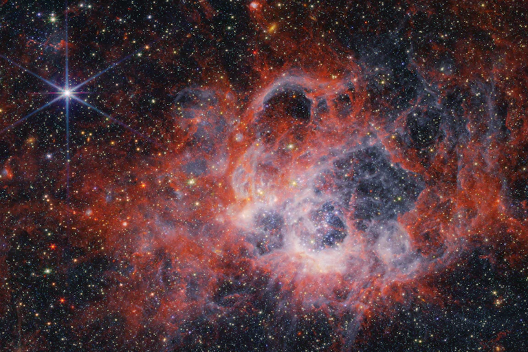 Clouds of red, pink and white gas and dust highlight this starscape.