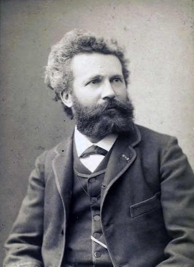 A black-and-white portrait of a man with bushy hair and a beard.