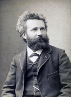 A black-and-white portrait of a man with bushy hair and a beard.
