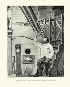 A vintage photograph of a man looking through a large telescope.