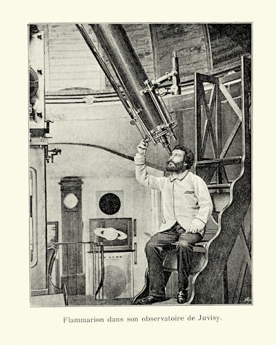 A vintage photograph of a man looking through a large telescope.