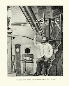 A vintage photograph of a man looking through a large telescope.