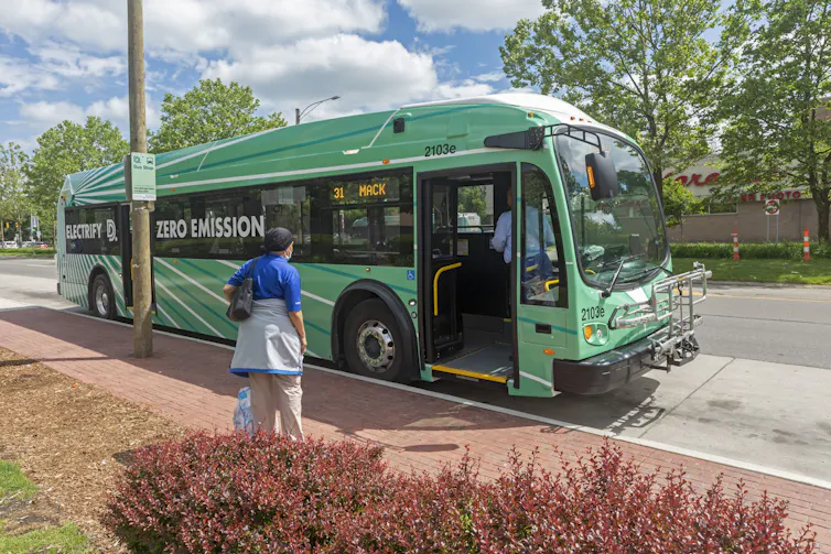 A green bus waits for a rider to board.