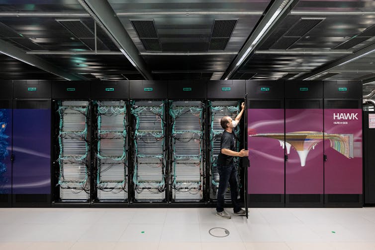 Foto de um homem abrindo um rack de servidores de computador.