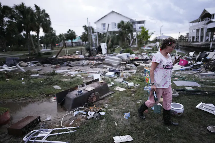 A woman walks through a field of debris.