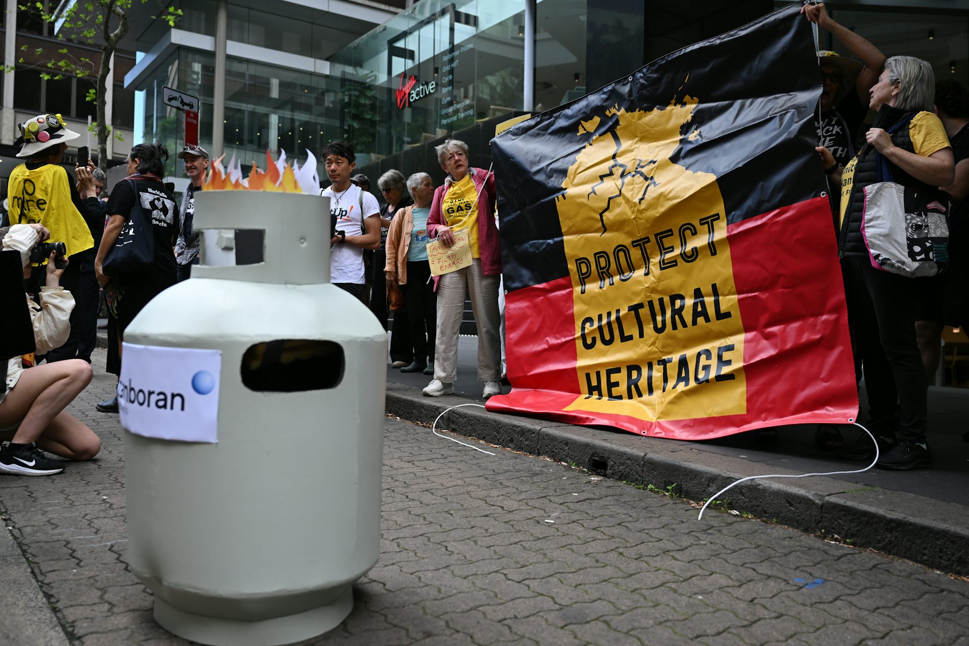 A gas canister with protesters holding a sign saying 'Protect cultural heritage'.