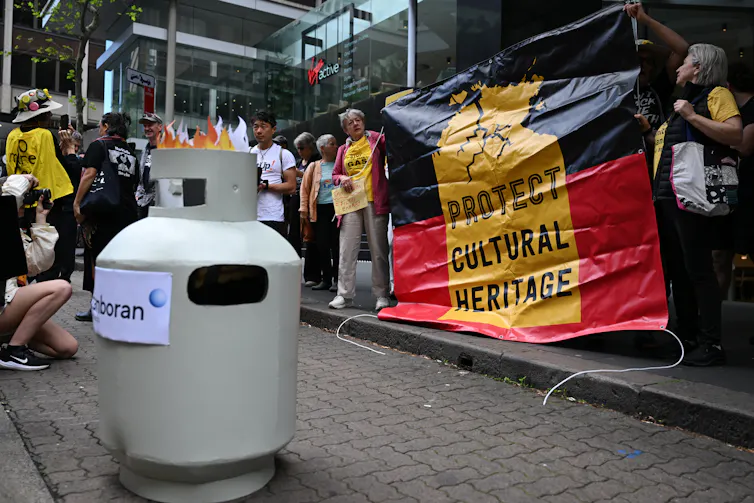 A gas canister with protesters holding a sign saying 'Protect cultural heritage'.