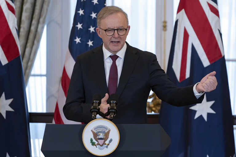 The Australian prime minister standing at a podium in front of US and Australian flags.