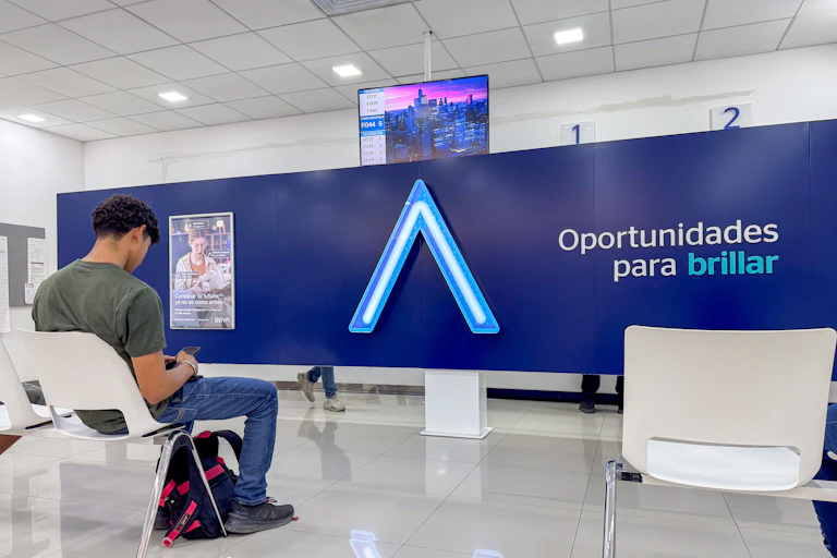 Un joven espera sentado enfrente de una pared con el lema "Oportunidades para brillar"