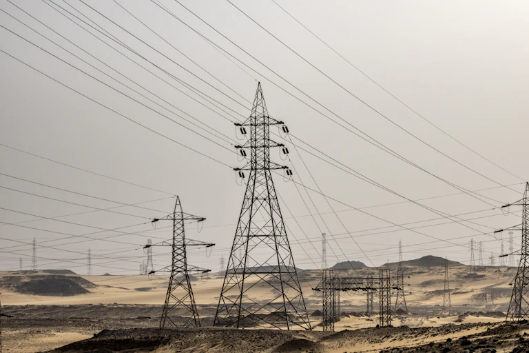 Long lines of electricity pylons and wire stretch out across a desert landscape