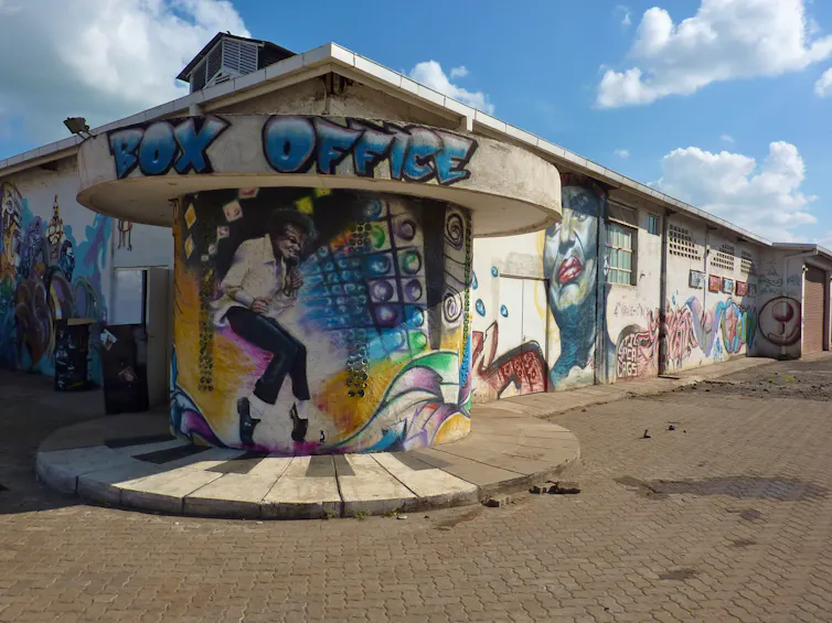 An urban structure with a circular building in front of it. This has been spray painted with the word