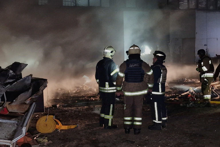 Ukrainian emergency service workers surrounded by smoke and damage after a Russian drone strike in April 2025.