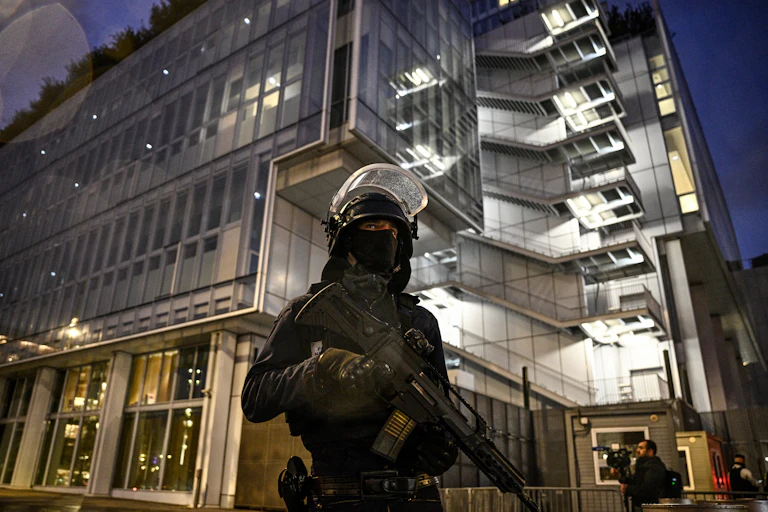 Un policier armé d'un fusil d'assaut monte la garde en attendant une escorte policière transportant le trafiquant de drogue français Mohamed Amra, dans le cadre de son extradition de la Roumanie vers la France, au palais de justice du Tribunal de Paris à Paris, le 25 février 2025. Amra, accusée d'être une figure majeure du trafic de drogue, était en fuite depuis sa libération en mai 2024 dans une embuscade qui a fait deux morts parmi les agents pénitentiaires. Il a été arrêté à Bucarest, ont annoncé le 22 février les ministères de l'Intérieur des deux pays. La police française a également arrêté 10 personnes soupçonnées d'avoir aidé le condamné, a déclaré un procureur. (Photo de JULIEN DE ROSA / AFP)