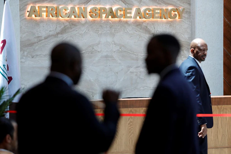 People silhouetted against a background where a sign on a wall says African Space Agency