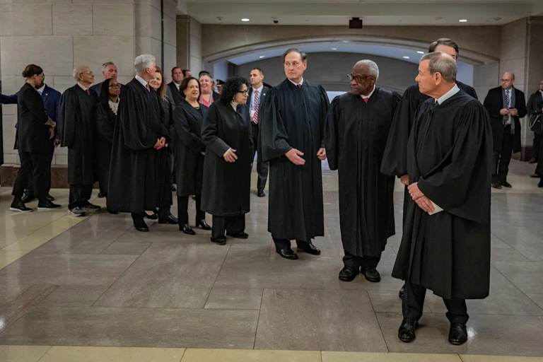 Supreme court chief justice John Roberts leads the other court justices, all wearing robes.