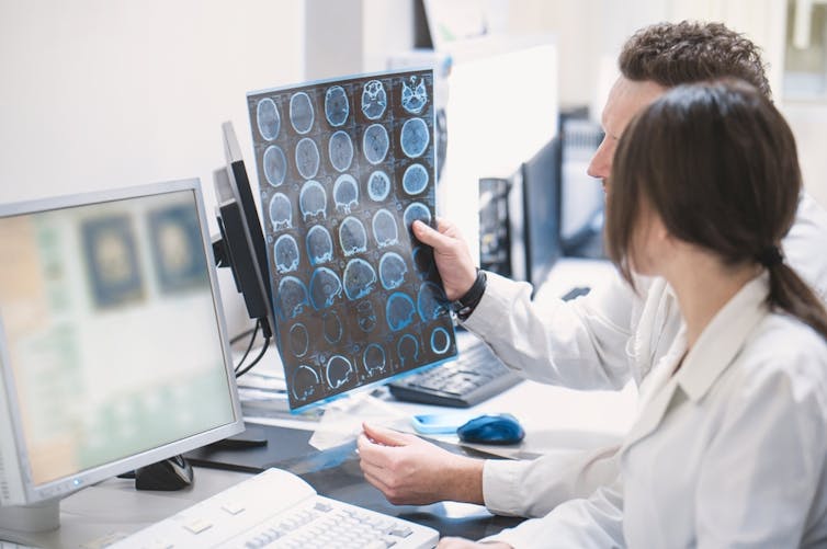 Two health workers looking at MRI scan images of brain