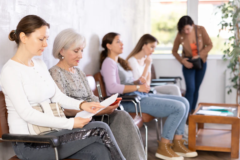 Line of women sit in a waiting room.