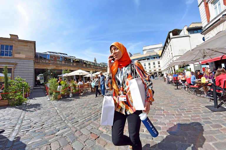A young Muslim wearing a headscarf and trouses, out shopping in London.