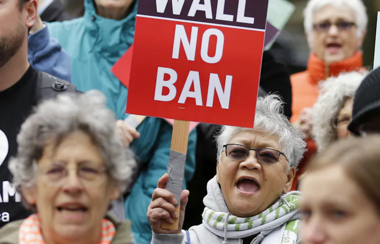 Several women participate in a protest as one holds a sign.