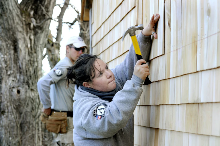 Two young people build a shed.