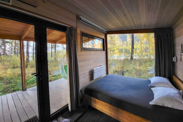 l'intérieur d'une minimaison avec vue la forêt depuis le lit. Ce n'est pas grand, mais ça a l'air très cozy.