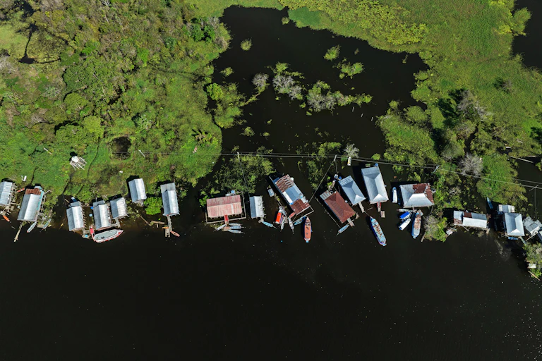 Casas y barcas de una comunidad en el agua de un río con vegetación alrededor