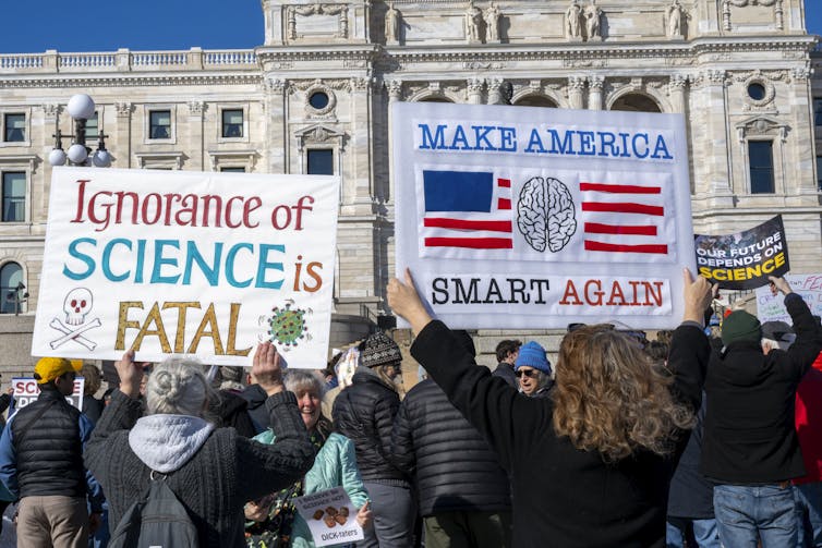 People outside the state capitol in St. Paul, Minnesota, hold signs reading 'Ignorance of science is fatal', 'Make America smart again' and 'Our future depends on science.'